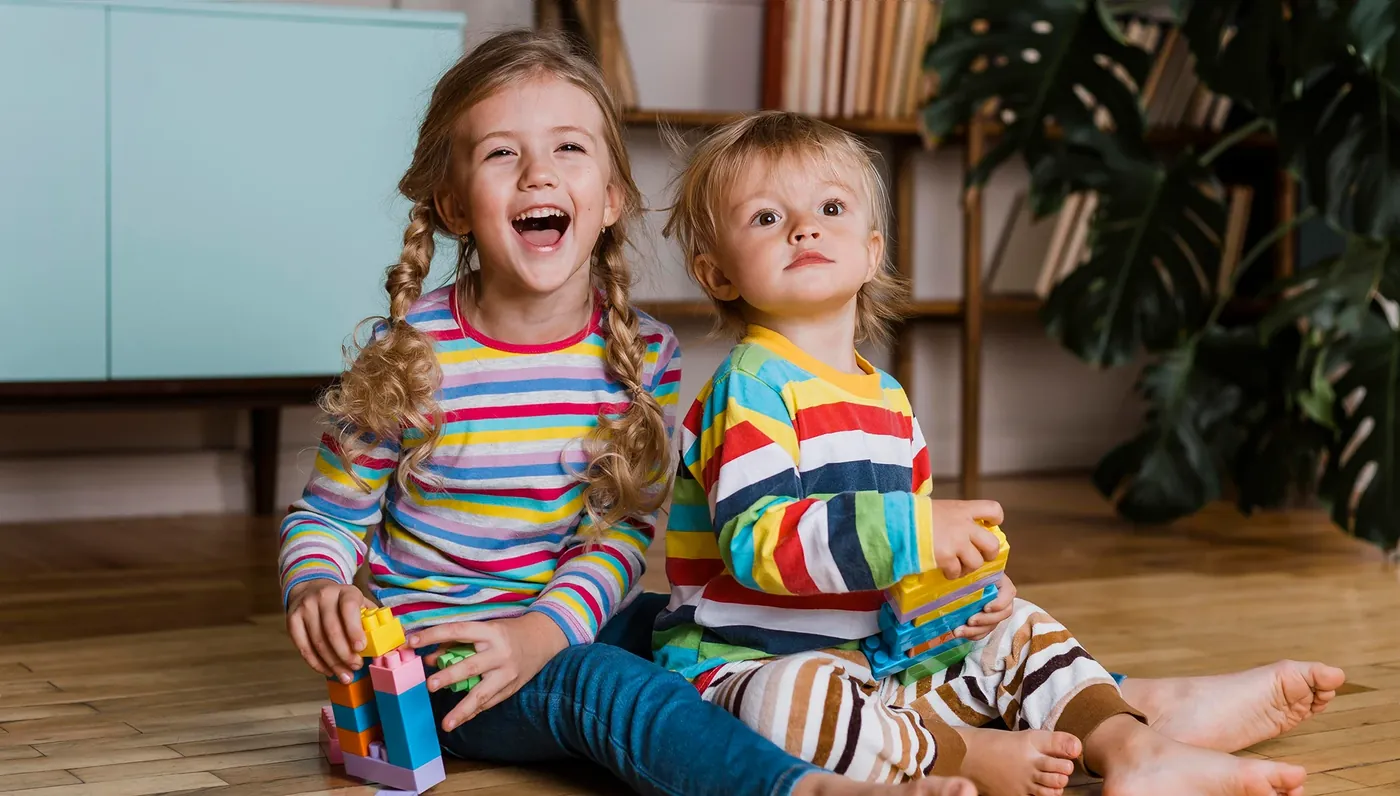Two young siblings laughing together at home